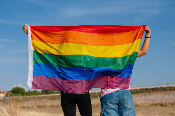 istock Two lesbian friends back to back with an LGBT pride flag. 1473183416