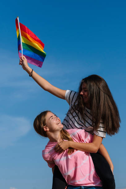 istock Two girlfriends kissing and waving LGBT pride flag. 1473183446