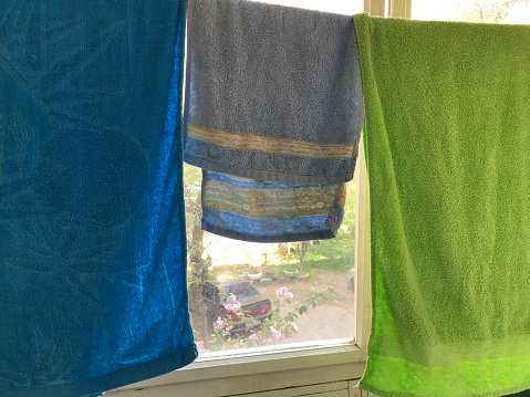 Three towels of different colors are drying on the balcony.