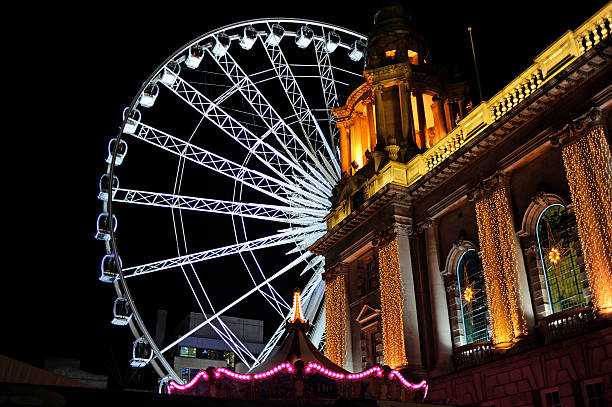 The Big Wheel Belfast The Big Wheel at Belfast City Hall at night. The Big Wheel is a temporary feature in Belfast city centre and will be due for relocation at some point. belfast stock pictures, royalty-free photos & images