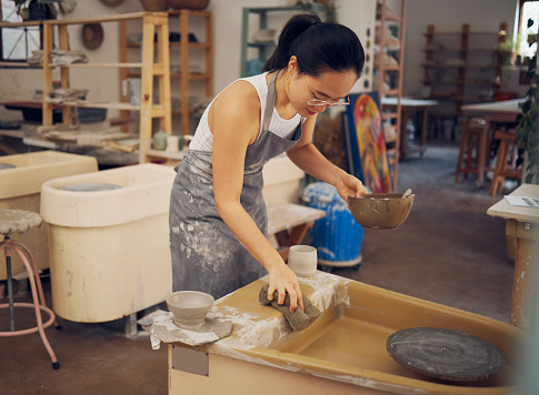 Pottery, startup business and woman cleaning in workshop for art class, production and manufacturing. Asian artist at creative potter workplace for clay or ceramic school, trade or process with pride