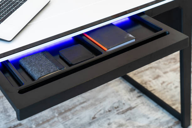 Top view of open wooden drawer white office table with blue lightning. Modern office table with light