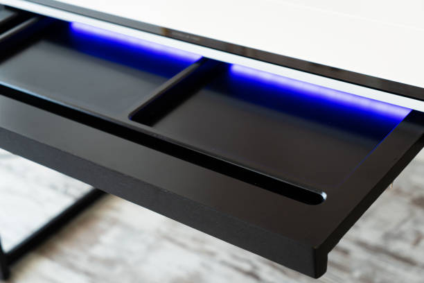 Top view of open wooden drawer white office table with blue lightning. Modern office table with light