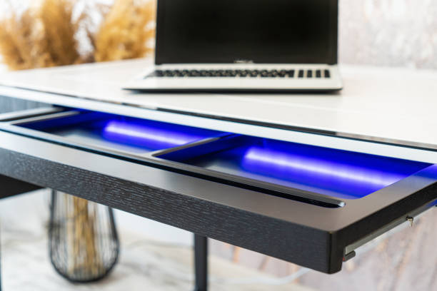 Top view of open wooden drawer white office table with blue lightning. Modern office table with light