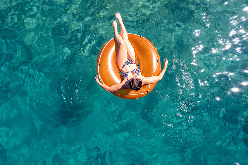 Young woman lying on sea ring in the clear sea.