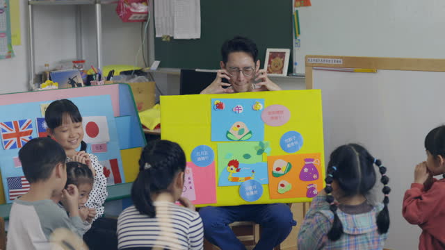 The Asian male teacher vividly explains the origin of the traditional festival of Dragon Boat Festival to his students.
