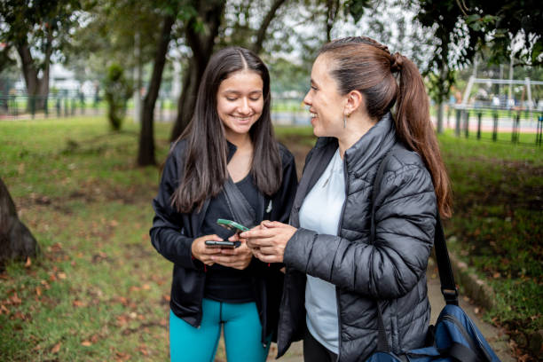 istock Mother and daughter talking while using mobile phone at public park 1473191523