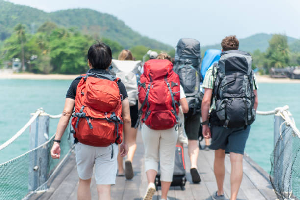 Travel and vacation concept: group of travelers with travel bags walking the boat from the port. stock photo