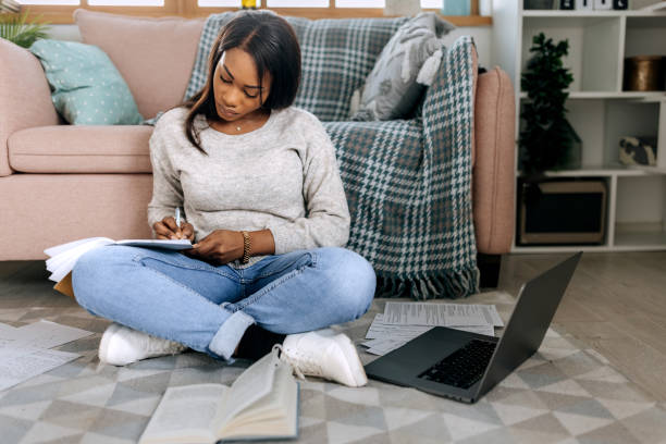 istock Young beautiful woman studying from her apartment while sitting on the floor 1473193129