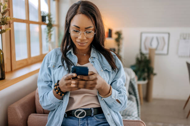 istock Young relaxed woman using mobile phone at home 1473193692