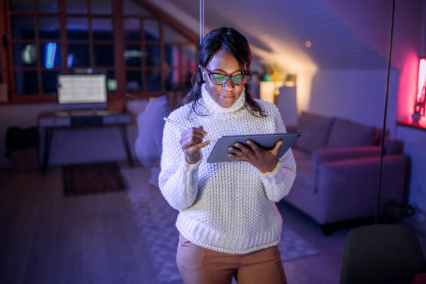 istock Young beautiful casually clothed businesswoman using digital tablet while working late night at home office 1473195447