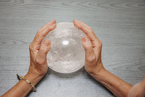 Hands of an elderly woman holding a rock crystal ball