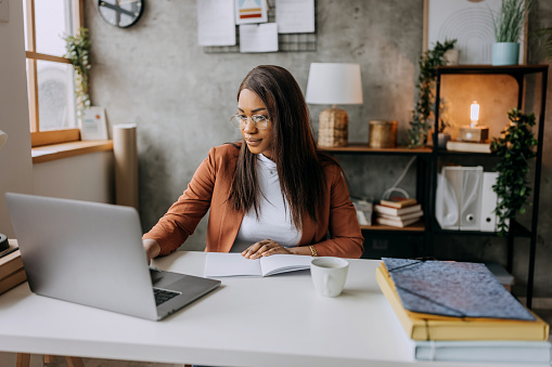 Beautiful well dressed businesswoman using laptop while working at home office