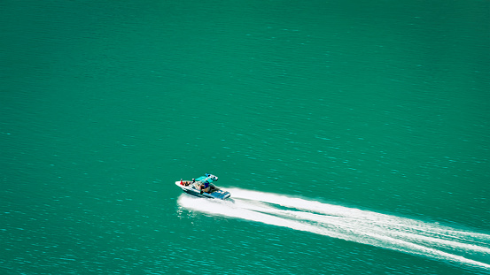 Aerial view of speed boat moving through Shasta lake during sunny day, California, USA.
