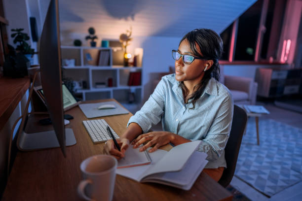 istock Young concentrated businesswoman taking notes while working from home office late night 1473196309