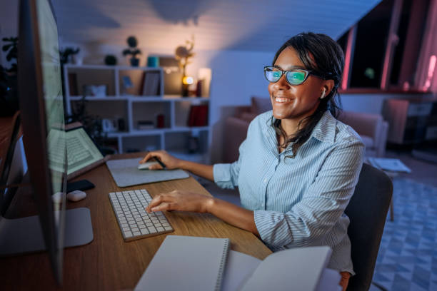 istock Smiling well dressed businesswoman working late on a desktop pc at home office 1473196312