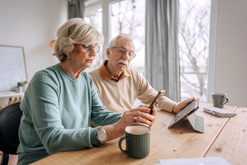 Senior couple using a digital tablet and phone at home