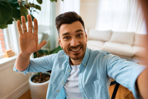 istock Cheerful man waving while making video call from home and looking at camera. 1473198448