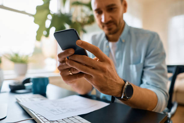istock Close up of entrepreneur using smart phone while working at home. 1473198483