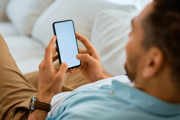 istock Close up of man texting on mobile phone while relaxing on the sofa. 1473198567