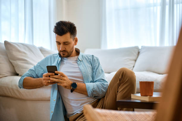 istock Mid adult man texting on cell phone while relaxing at home. 1473198602