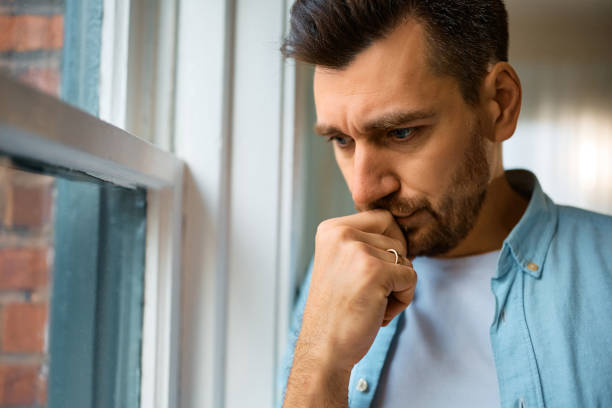 istock Worried man thinking of his problems by the window at home. 1473198660