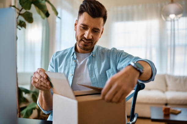 istock Happy man unboxing home delivered package. 1473199420