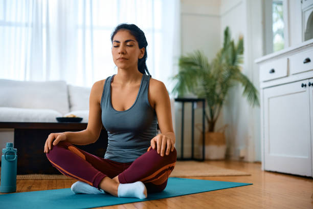 istock Athletic woman meditating with eyes closed while exercising Yoga at home. 1473199600