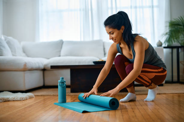 istock Happy athletic woman folding exercise mat after working out at home. 1473199630