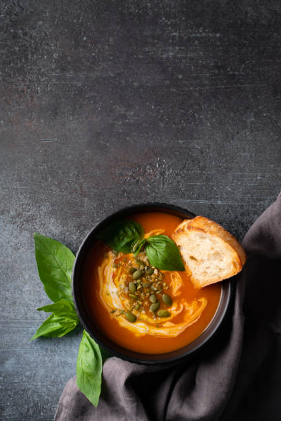istock Pumpkin soup with bread, seeds and basil leaf on dark background 1473199646