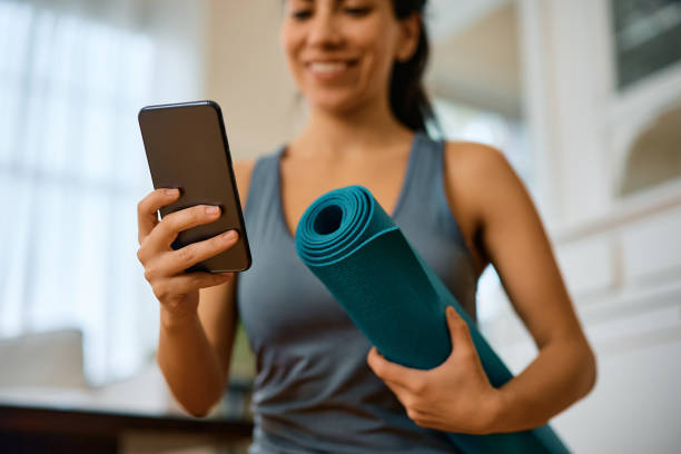 istock Close up of sportswoman using cell phone while exercising at home. 1473199657