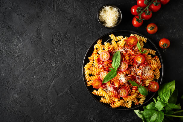 istock Fusilli pasta with tomatoes, basil, parmesan, and sauce on back background 1473199715