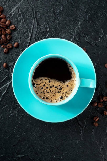 istock Teal coffee cup and coffee beans, top shot on a black background 1473199852