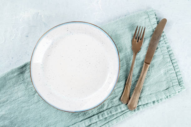 istock An empty white plate, with a fork and a knife, overhead flat lay shot 1473199962