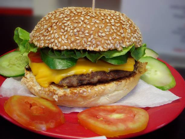istock Close up of a cheese burger with sesame seeds on a red plate 1473200432
