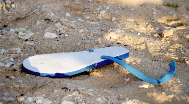 istock A blue and white slipper with broken straps on the sand 1473200433