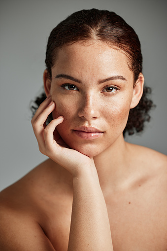 Black woman, skincare and natural face for beauty cosmetic and glow treatment campaign portrait. Healthy body care of model with beautiful freckles on hydrated skin in gray studio background.