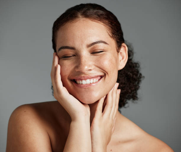 rostro, belleza y satisfacción con una mujer negra modelo en estudio sobre fondo gris para promover el cuidado natural de la piel. facial, bienestar y maquillaje con una atractiva joven feliz con los cosméticos - tan skin fotografías e imágenes de stock