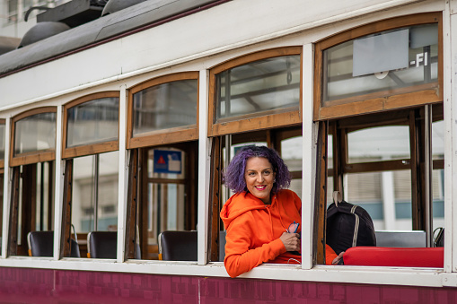 Smiling Woman In Orange Shirt Looking Out The Window On The Tram Lisbon, Portugal.