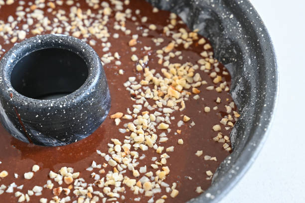 Walnut and cocoa liquid dough in a bundt cake tin on white background