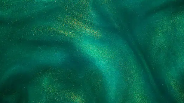 Photo of Abstract magic green background with golden sparkles.
