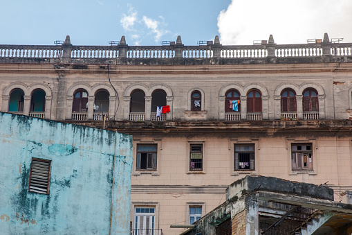 Havana, Cuba - January 23, 2023: Facade of an old building with several buildings and balconies. Clothes hang from windows and balconies; no people are on the scene.