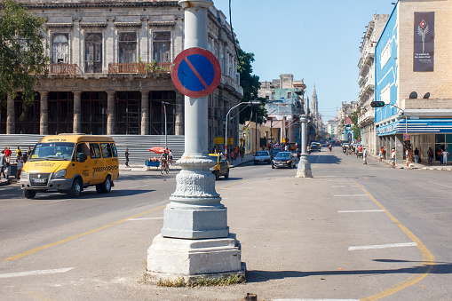 Havana, Cuba - January 23, 2023: A street in a downtown area in the daytime. Vehicles are on the road, and incidental people are walking along.