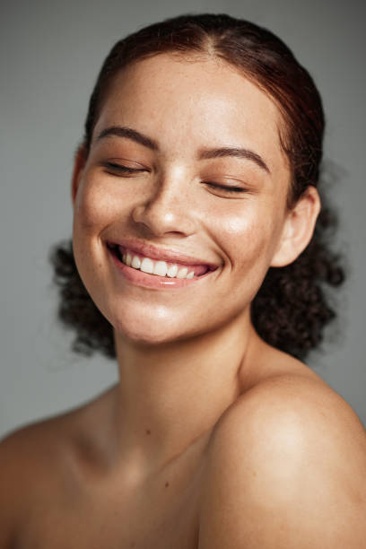 rostro, belleza y cuidado de la piel con una mujer negra modelo en estudio sobre fondo gris para promover el cuidado natural. facial, bienestar y maquillaje con una atractiva joven mujer feliz con su producto para la piel - beauty treatment fotos fotografías e imágenes de stock