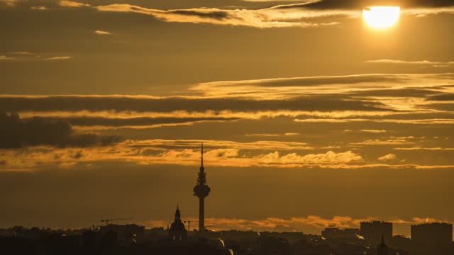 Timelapse of torre españa with clouds and big sun on the horizon. Skyline of Madrid