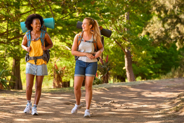 Two Female Friends With Backpacks On Vacation Hiking Through Countryside Together stock photo