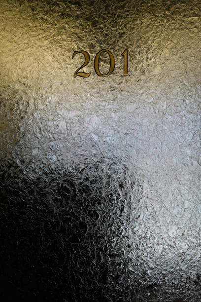 Crackled glass in office door window with numbers and dim lighting.