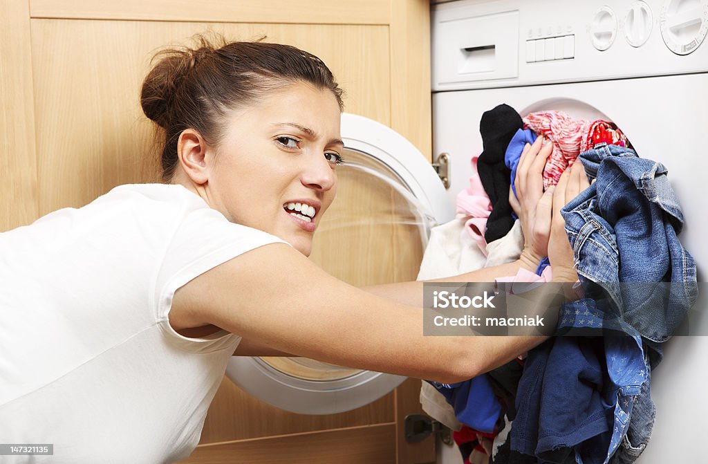 Housewife doing laundry A close up of a young wife putting clothes into a washing machine Adult Stock Photo
