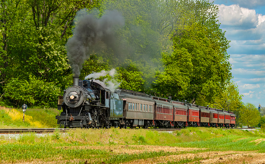 View of an Antique Restored Steam Passenger Train Approaching Along a Lone Rail Road Track on a Spring Day