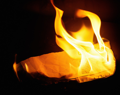 Newspaper clipping (simulated) goes up in real flames. Text written by the photographer, so free of third-party copyright.